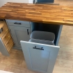kitchen island with wood top with trash bins in cabinet